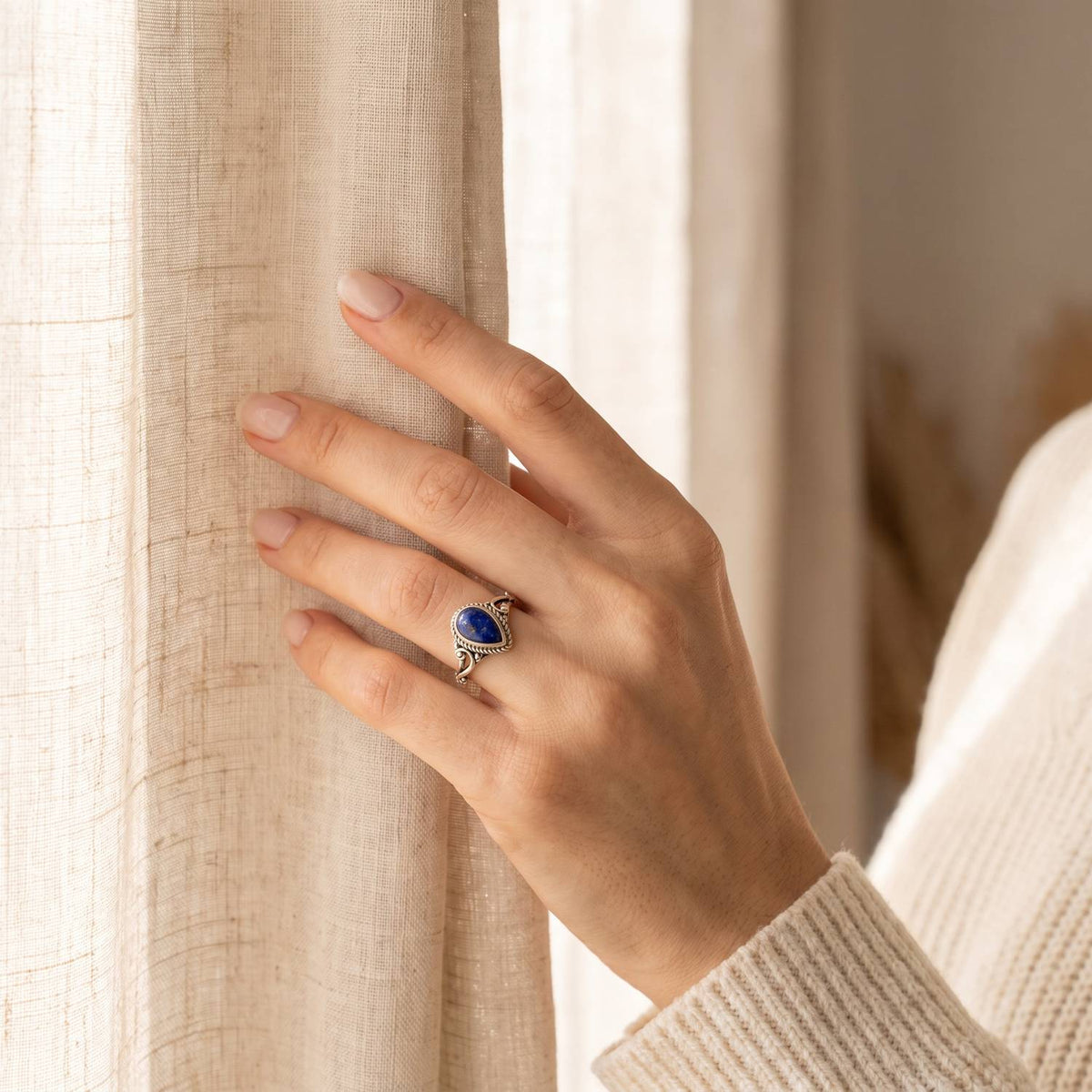 Frau trägt einen Lapislazuliring aus Silber am Fenster