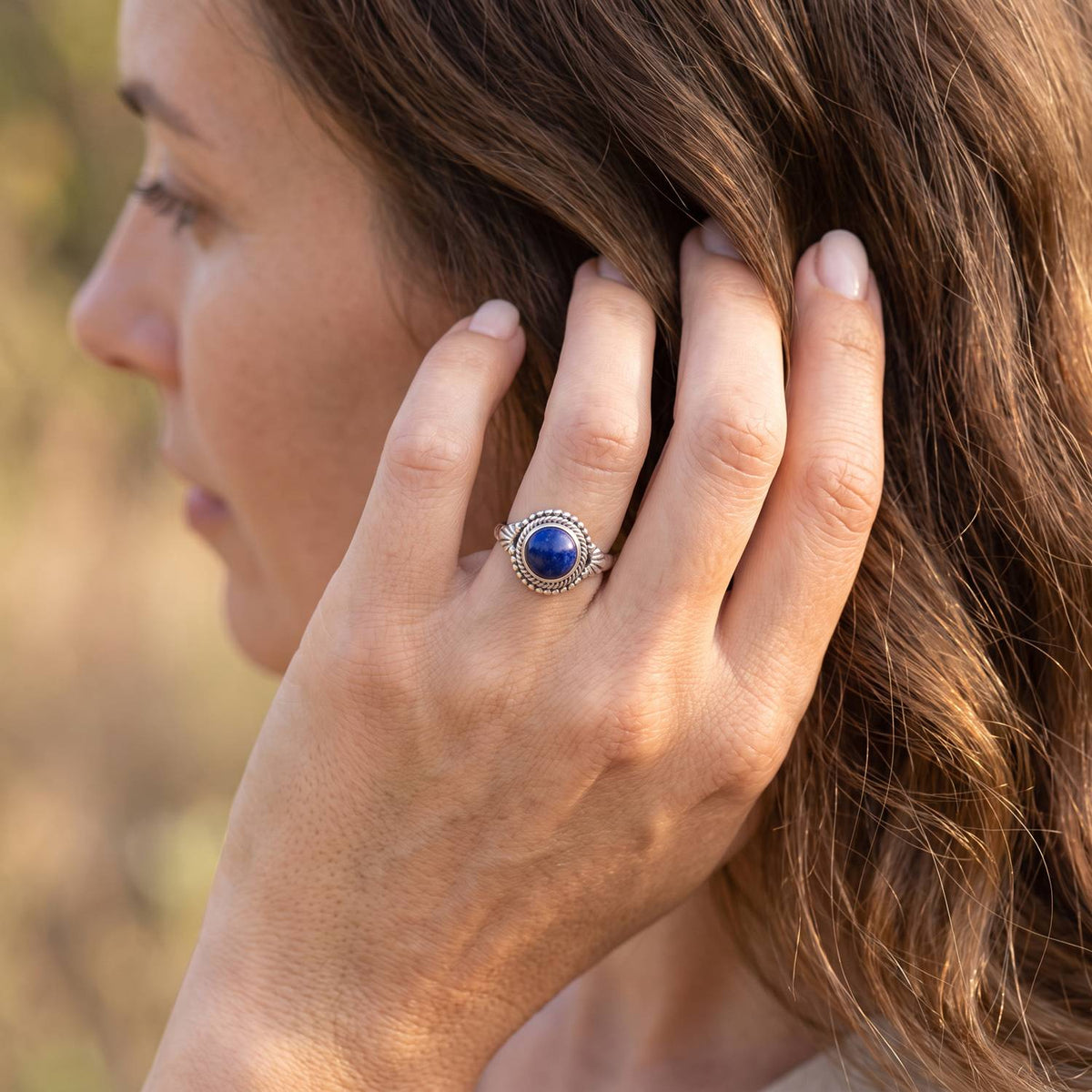 Frau trägt Silberring mit Lapislazuli an der Hand am Haar