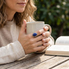 [KI] Lapislazuliring aus Silber getragen beim Lesen mit einer Tasse