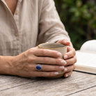 [KI] Lapislazuliring aus Silber getragen beim Lesen mit einer Tasse