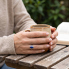 [KI] Lapislazuliring aus Silber getragen beim Lesen mit einer Tasse