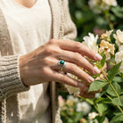 [KI] Silberring mit Malachit an der Hand zwischen Blumen
