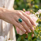 [KI] Silberring mit Malachit an der Hand zwischen Blumen