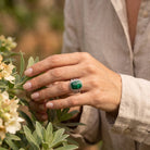 [KI] Silberring mit Malachit an der Hand zwischen Blumen
