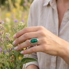 [KI] Silberring mit Malachit an der Hand zwischen Blumen