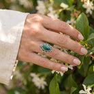 [KI] Silberring mit Malachit an der Hand zwischen Blumen