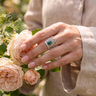 [KI] Silberring mit Malachit an der Hand zwischen Blumen
