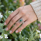 [KI] Silberring mit Malachit an der Hand zwischen Blumen