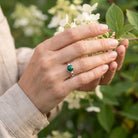 [KI] Silberring mit Malachit an der Hand zwischen Blumen