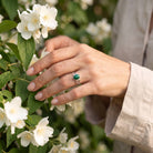 [KI] Silberring mit Malachit an der Hand zwischen Blumen