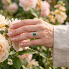 [KI] Silberring mit Malachit an der Hand zwischen Blumen