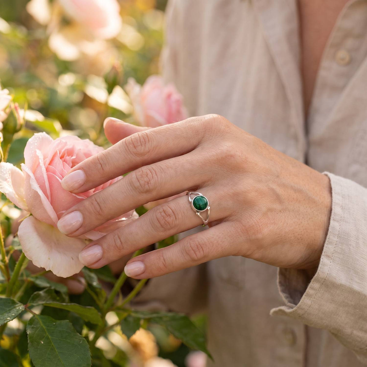 Silberring mit Malachit an der Hand zwischen Blumen