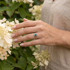 [KI] Silberring mit Malachit an der Hand zwischen Blumen
