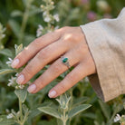 [KI] Silberring mit Malachit an der Hand zwischen Blumen