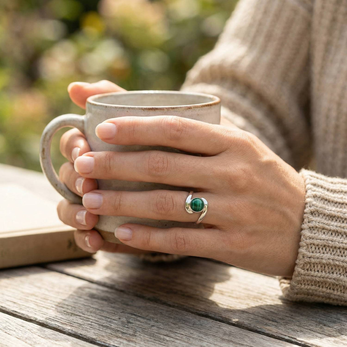 Malachitring aus Silber getragen beim Lesen mit einer Tasse
