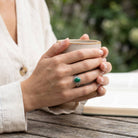 [KI] Malachitring aus Silber getragen beim Lesen mit einer Tasse