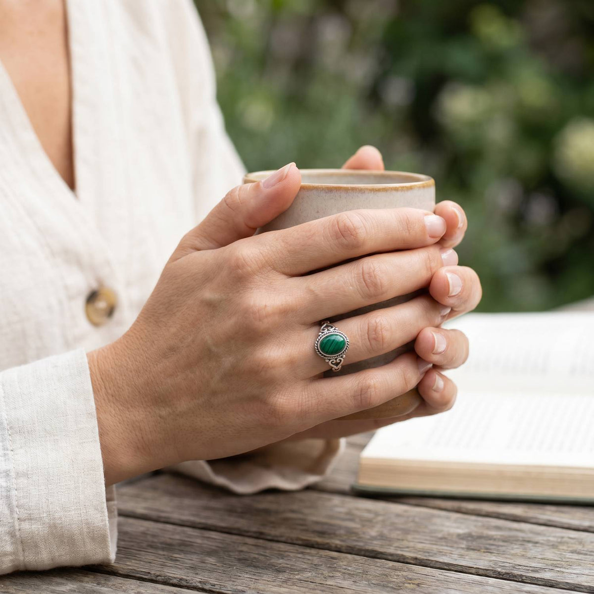 Malachitring aus Silber getragen beim Lesen mit einer Tasse