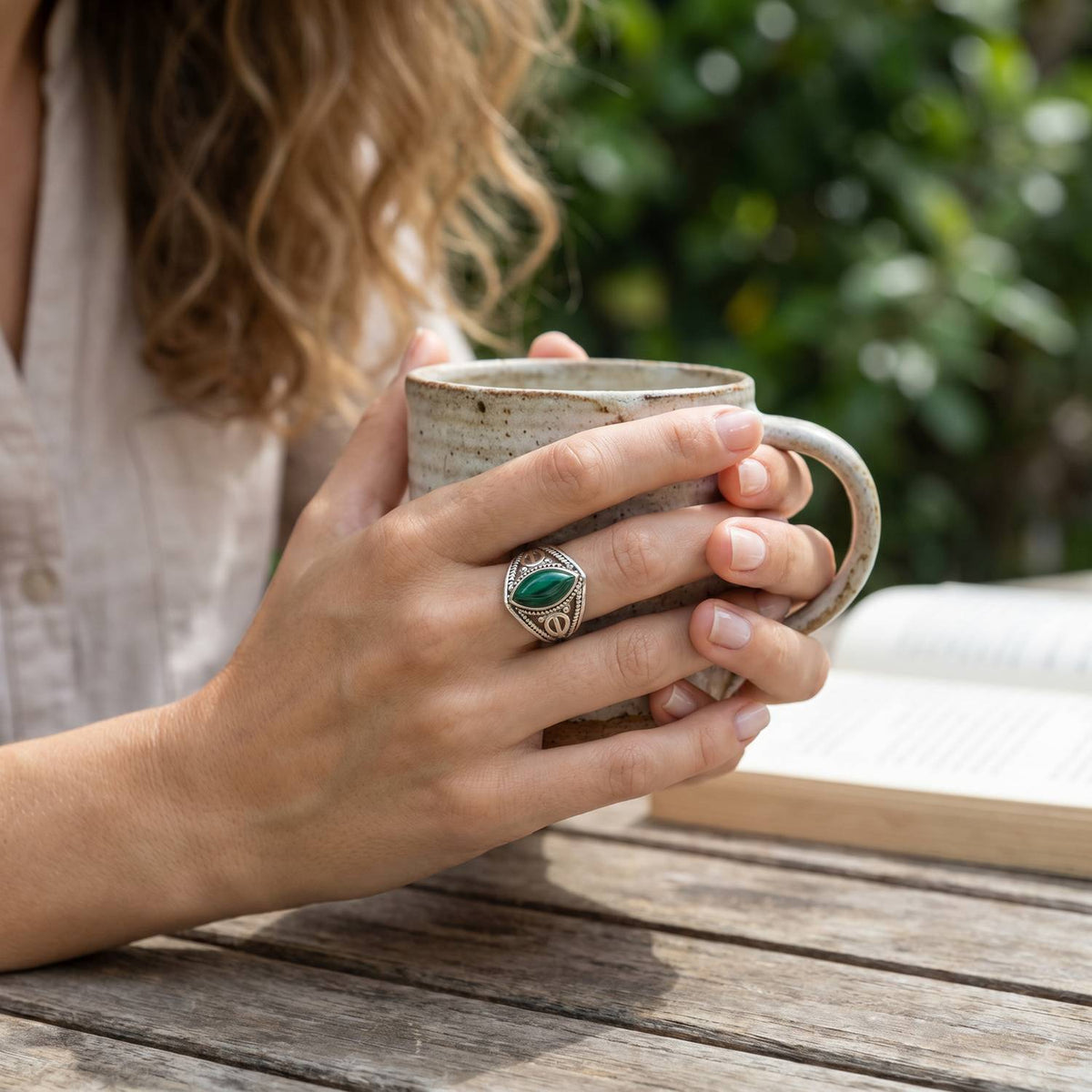 Malachitring aus Silber getragen beim Lesen mit einer Tasse