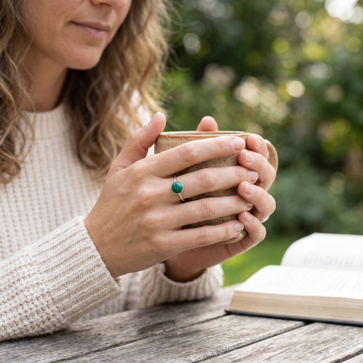 Malachitring aus Silber getragen beim Lesen mit einer Tasse