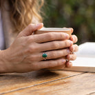 [KI] Malachitring aus Silber getragen beim Lesen mit einer Tasse