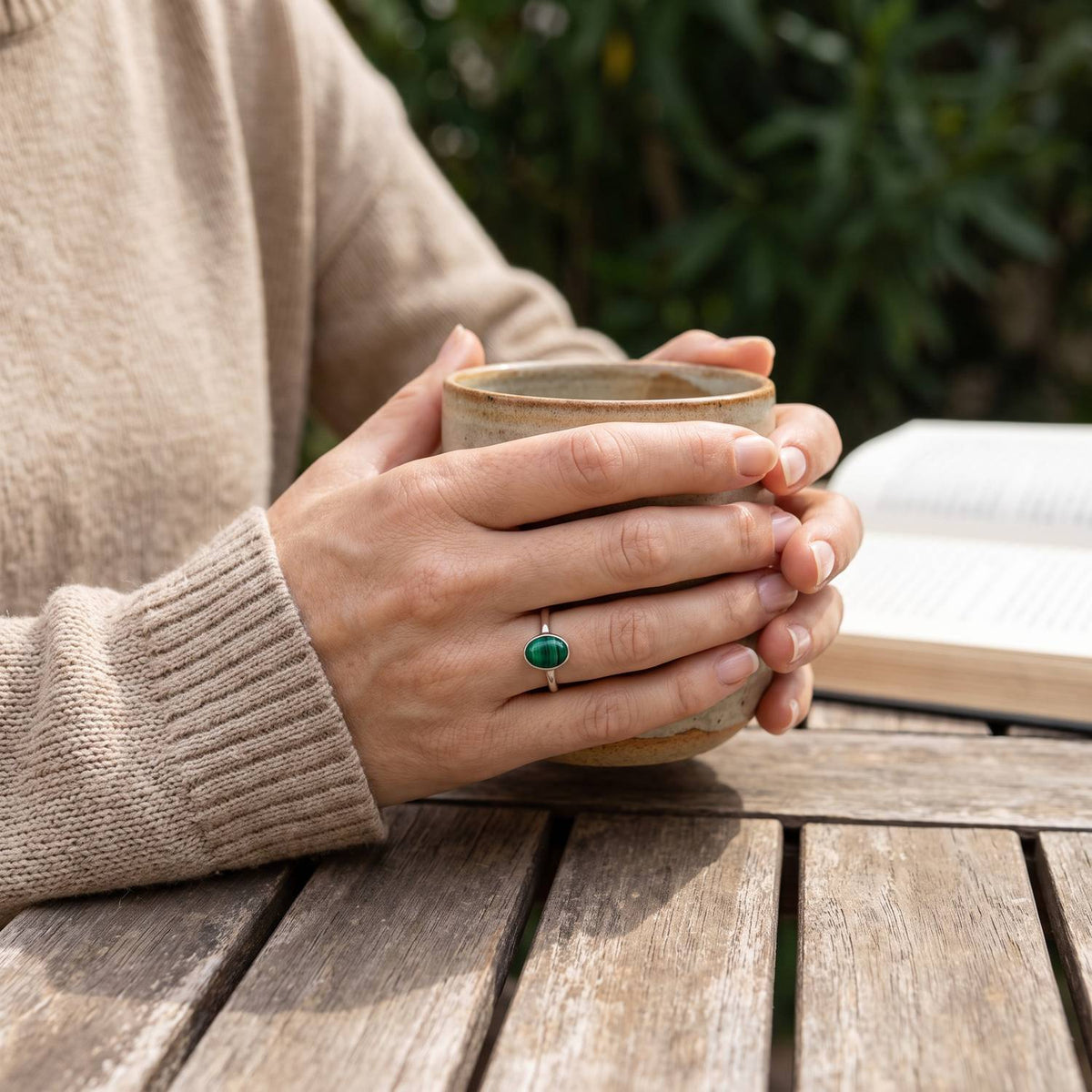 Malachitring aus Silber getragen beim Lesen mit einer Tasse