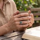 [KI] Malachitring aus Silber getragen beim Lesen mit einer Tasse