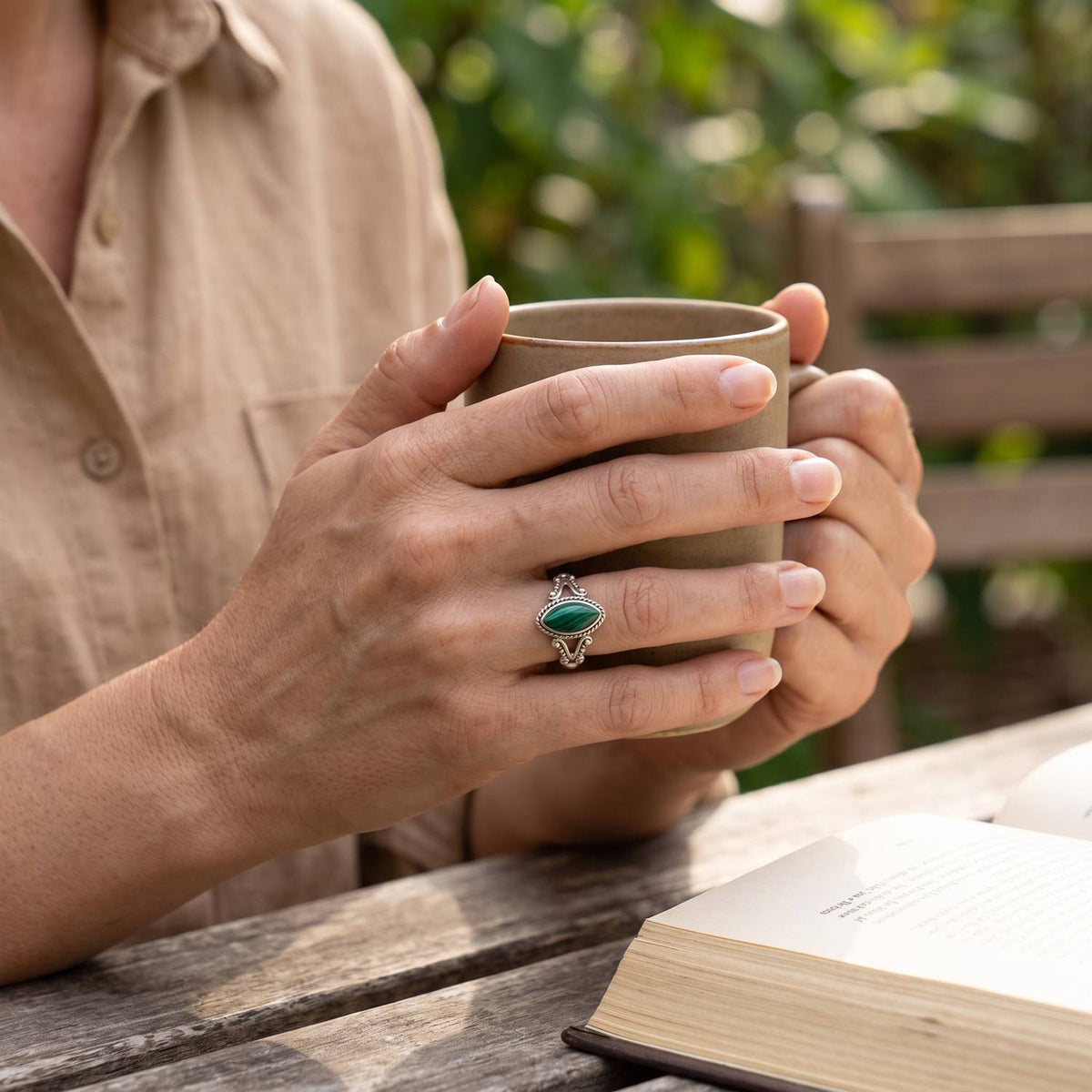 Malachitring aus Silber getragen beim Lesen mit einer Tasse