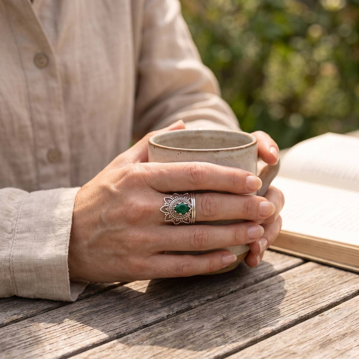 Malachitring aus Silber getragen beim Lesen mit einer Tasse