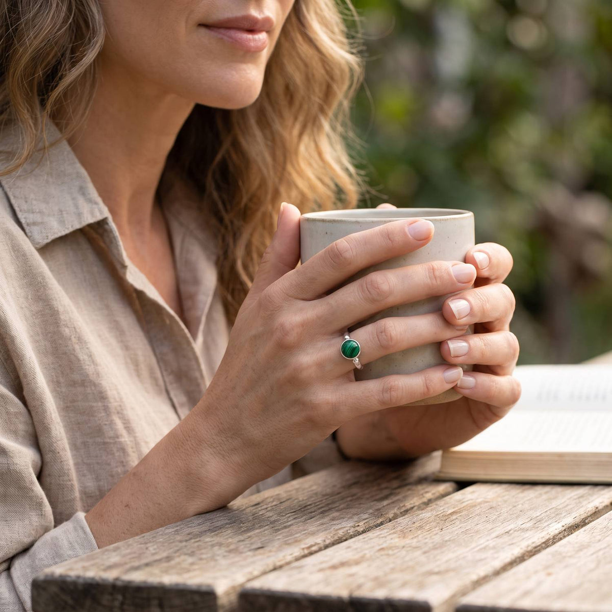 Malachitring aus Silber getragen beim Lesen mit einer Tasse