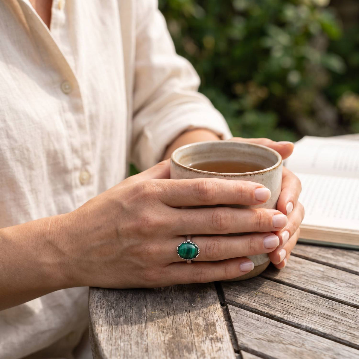 Malachitring aus Silber getragen beim Lesen mit einer Tasse