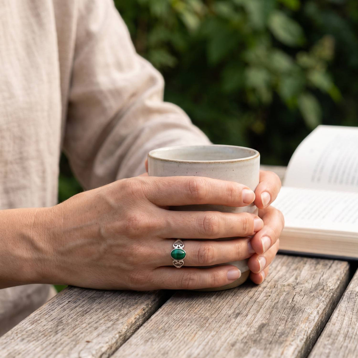 Malachitring aus Silber getragen beim Lesen mit einer Tasse