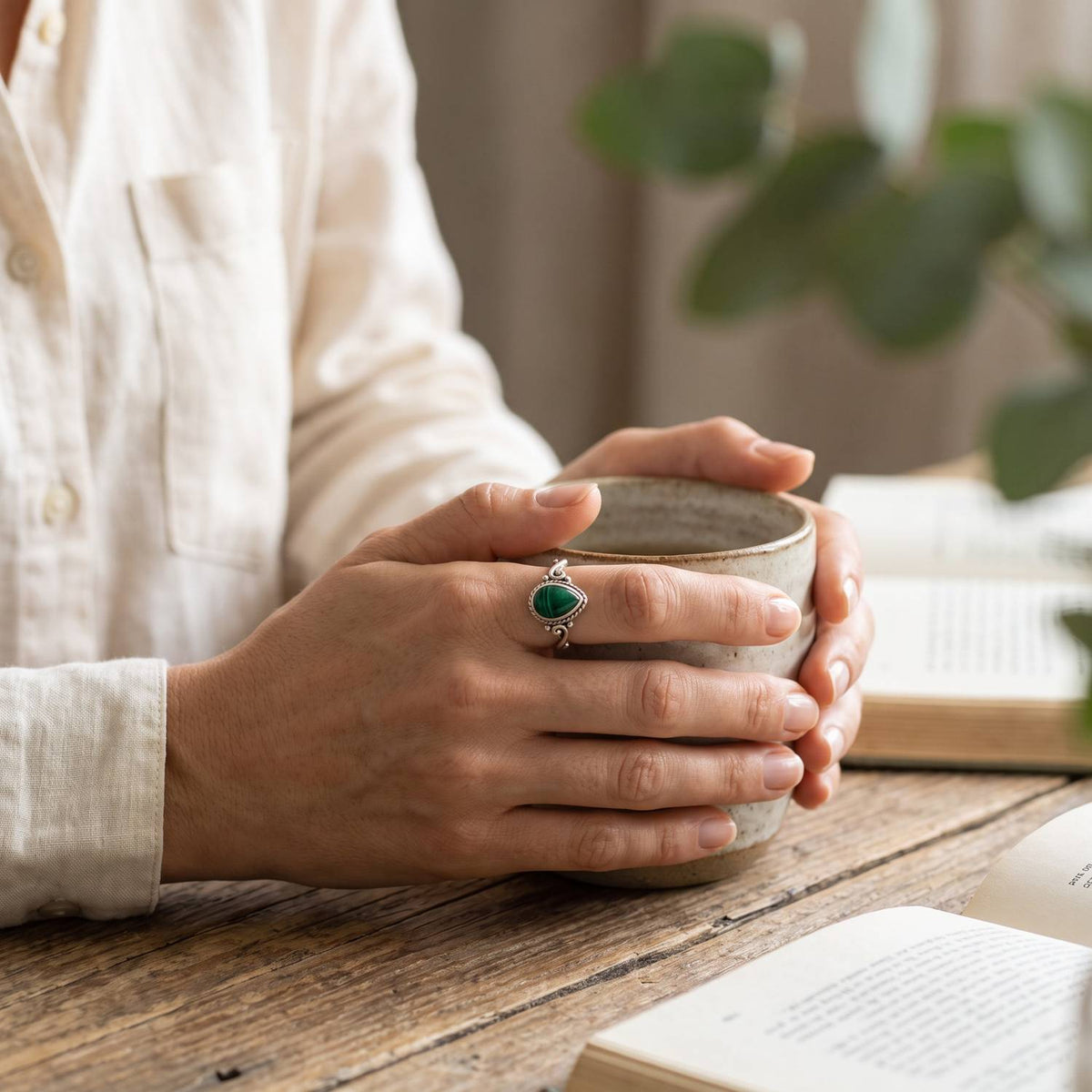 Malachitring aus Silber getragen beim Lesen mit einer Tasse