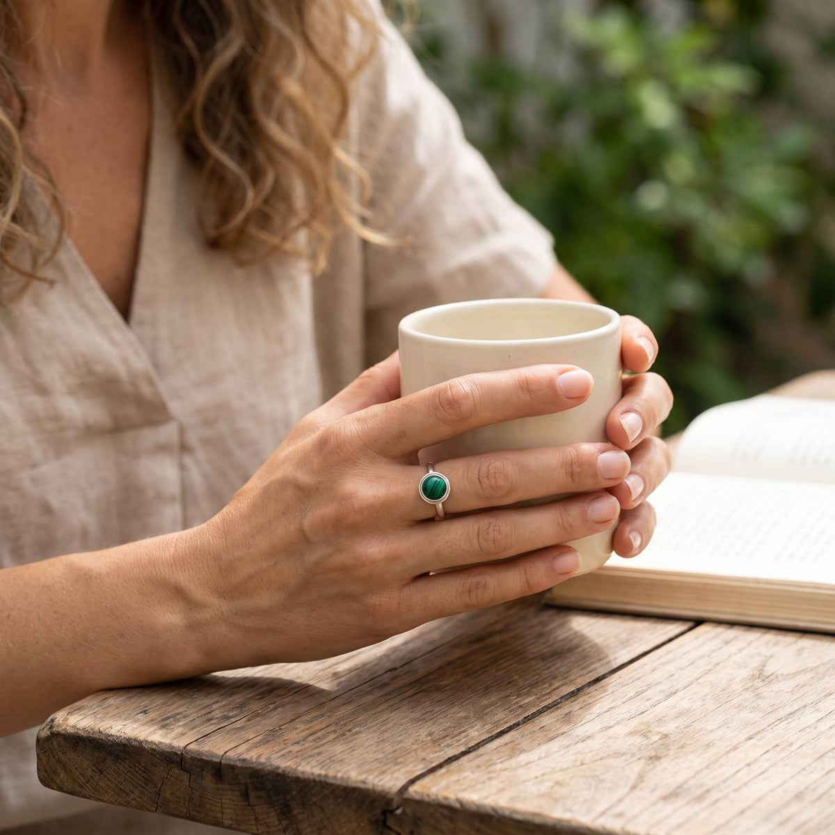 Malachitring aus Silber getragen beim Lesen mit einer Tasse