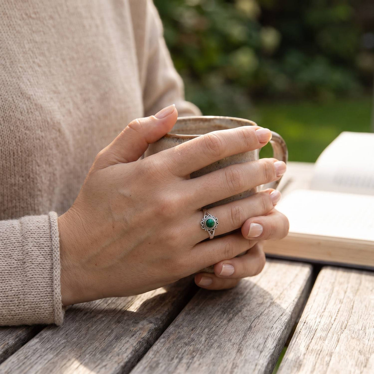 Malachitring aus Silber getragen beim Lesen mit einer Tasse