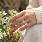 [KI] Silberring mit Mondstein an der Hand zwischen Blumen