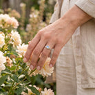 [KI] Silberring mit Mondstein an der Hand zwischen Blumen