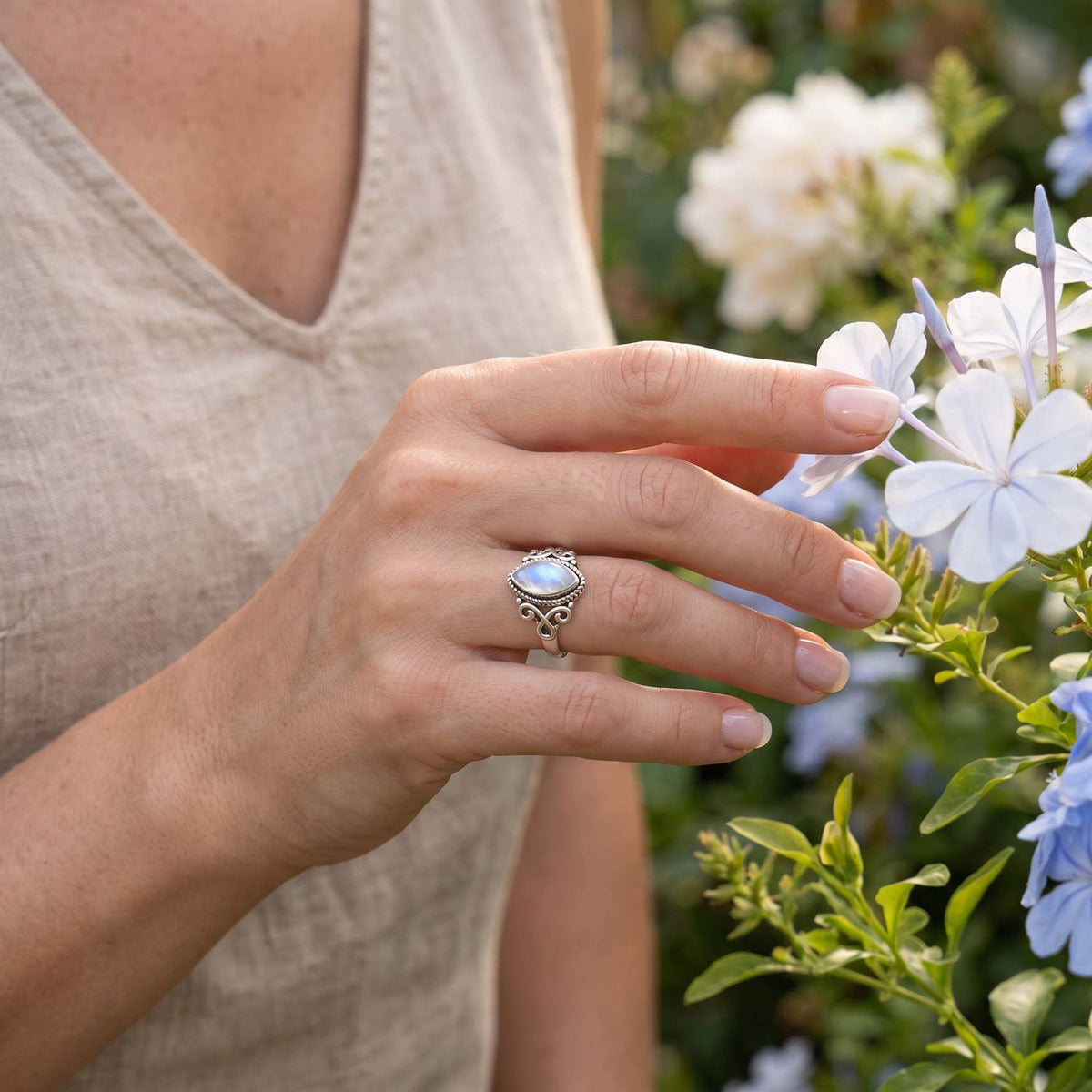 Silberring mit Mondstein an der Hand zwischen Blumen