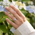[KI] Silberring mit Mondstein an der Hand zwischen Blumen