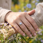 [KI] Silberring mit Mondstein an der Hand zwischen Blumen