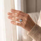 [KI] Frau trägt einen Mondsteinring aus Silber am Fenster