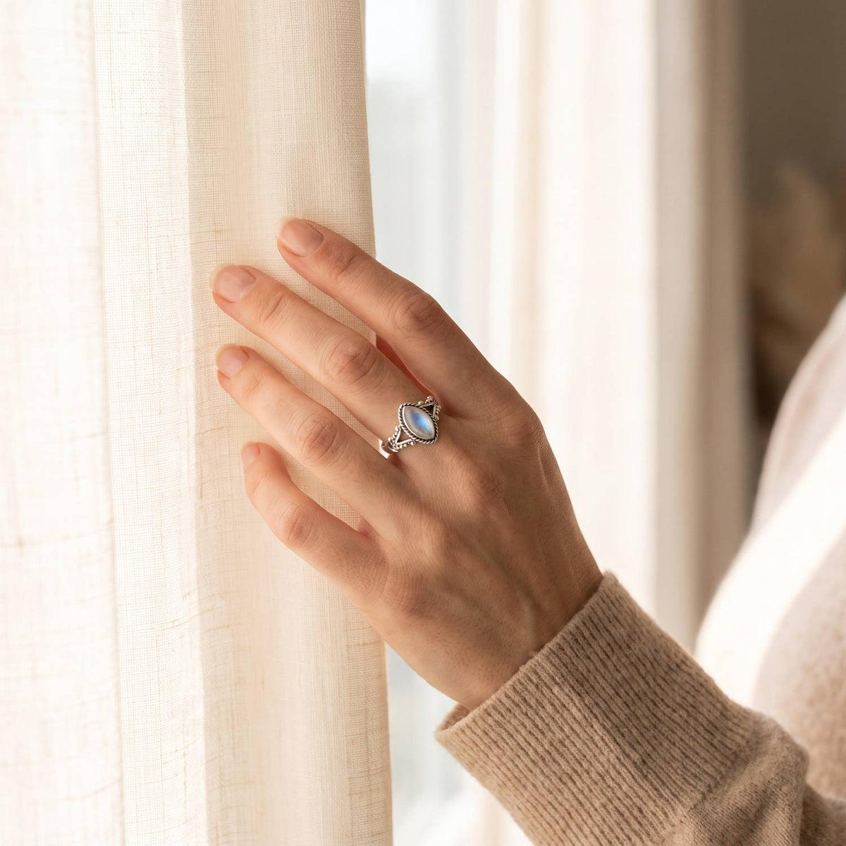 Frau trägt einen Mondsteinring aus Silber am Fenster