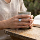 [KI] Mondsteinring aus Silber getragen beim Lesen mit einer Tasse