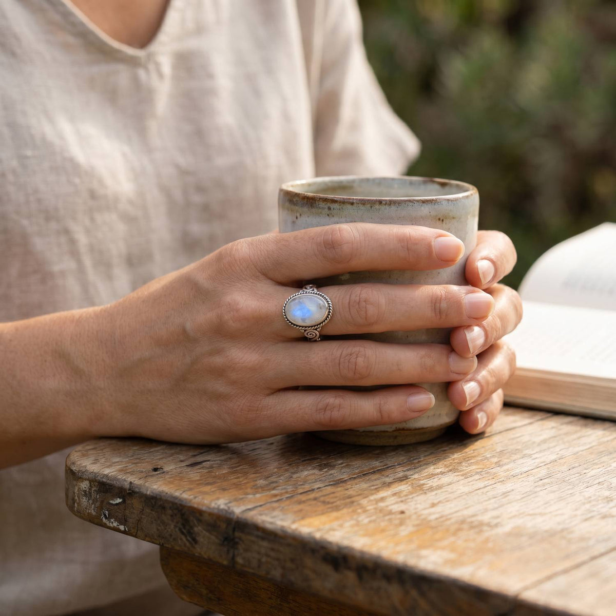 Mondsteinring aus Silber getragen beim Lesen mit einer Tasse