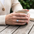 [KI] Mondsteinring aus Silber getragen beim Lesen mit einer Tasse
