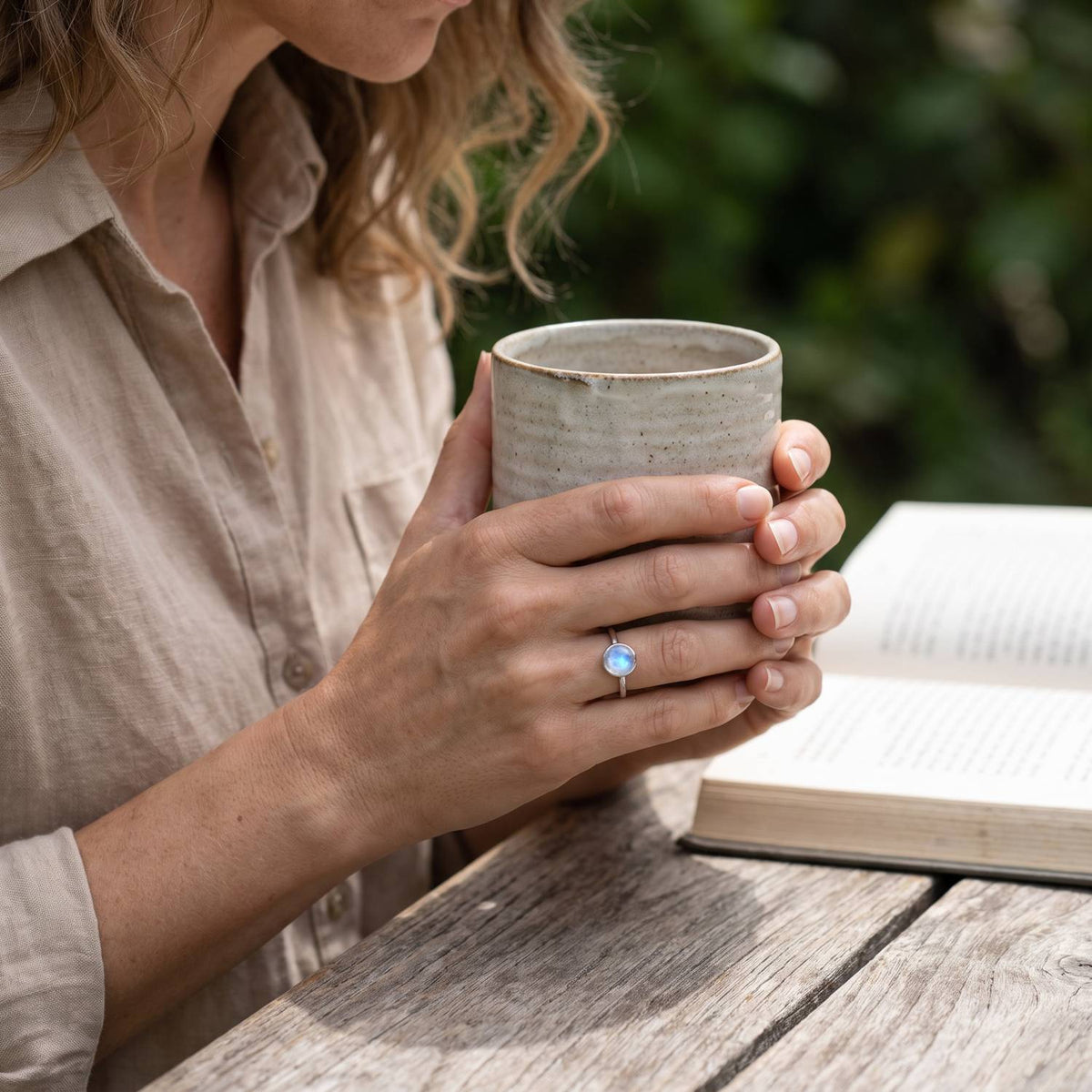 Mondsteinring aus Silber getragen beim Lesen mit einer Tasse