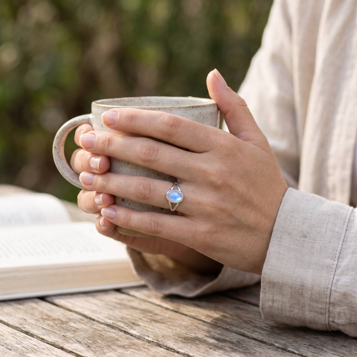 Mondsteinring aus Silber getragen beim Lesen mit einer Tasse