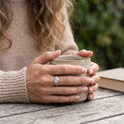 [KI] Mondsteinring aus Silber getragen beim Lesen mit einer Tasse