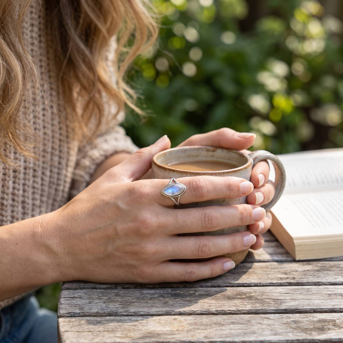 Mondsteinring aus Silber getragen beim Lesen mit einer Tasse