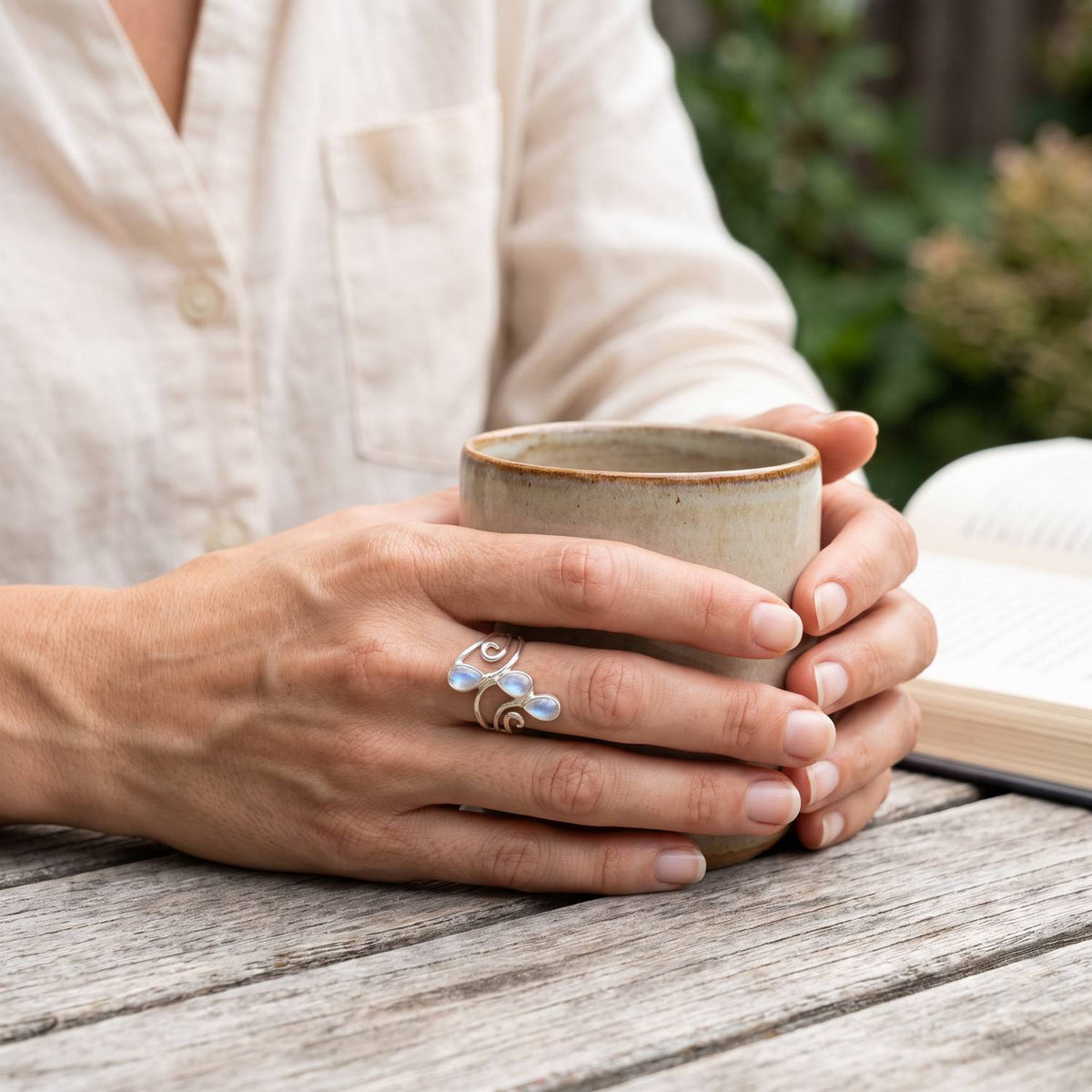 Mondsteinring aus Silber getragen beim Lesen mit einer Tasse