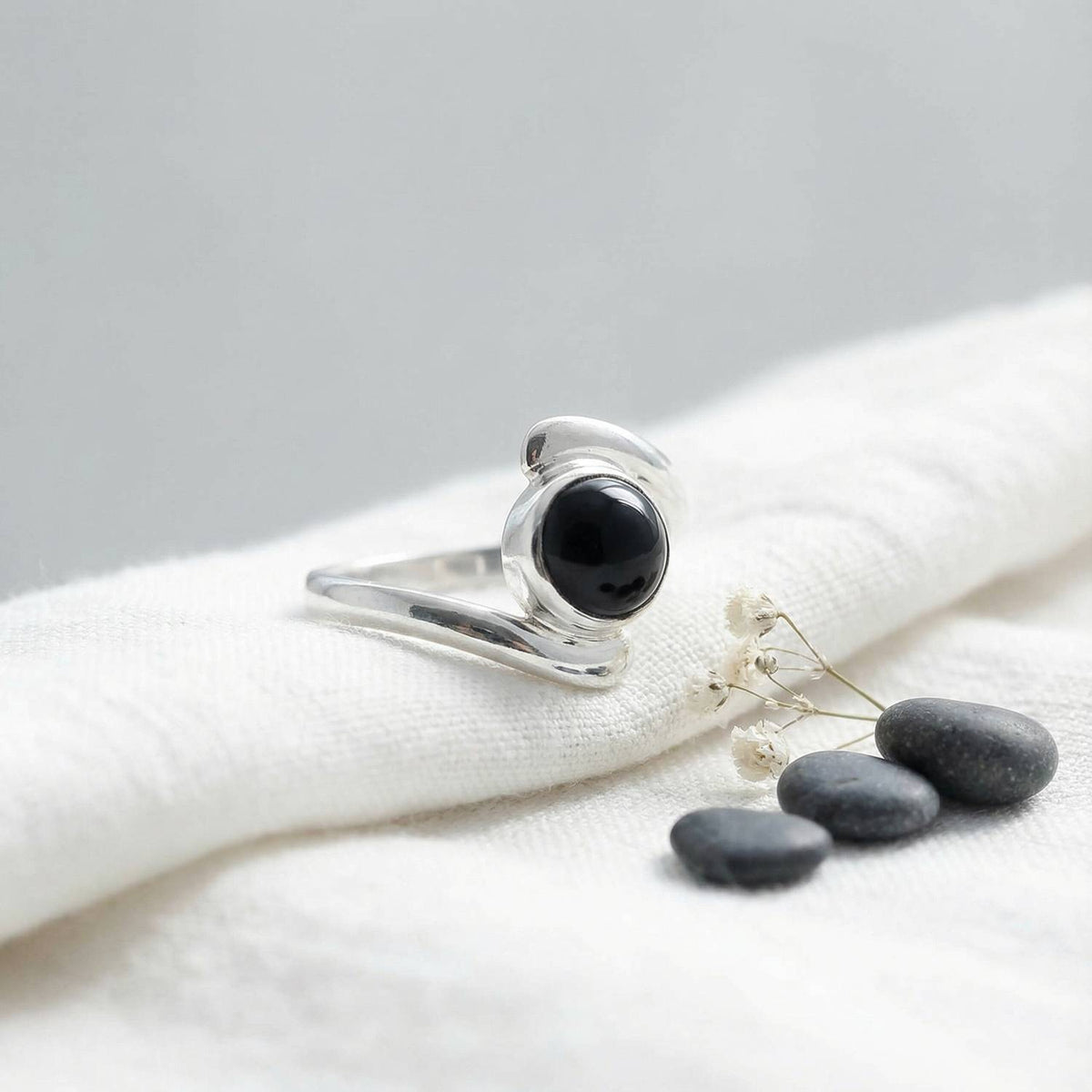 Silberring mit Onyx auf hellem Stoff